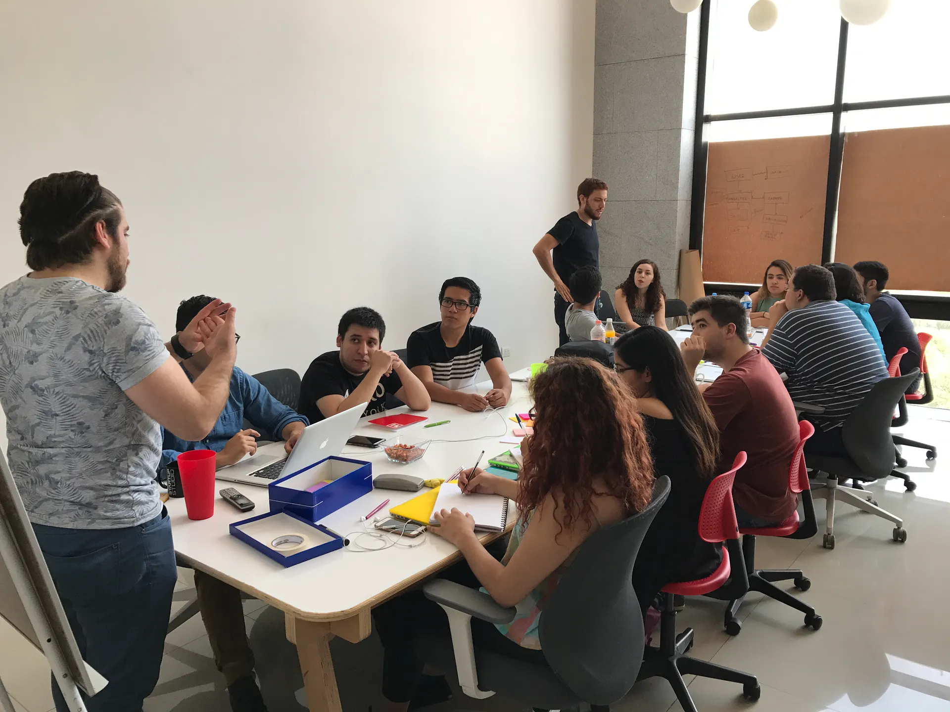 Young design and development interns around a table learning to run a Design Sprint during Icalia’s Summer Internship