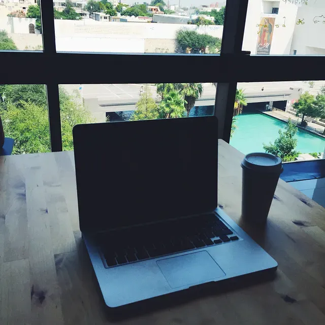 Laptop open with clear view in the background, from an open space office.